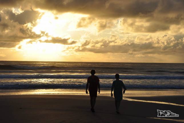 O Rodrigo e sua mãe caminham na praia enquanto o dia nasce em Punta del Diablo, no litoral do Uruguai